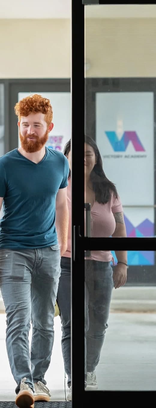 Two people smiling as they walk in through the front doors of Victory Church.