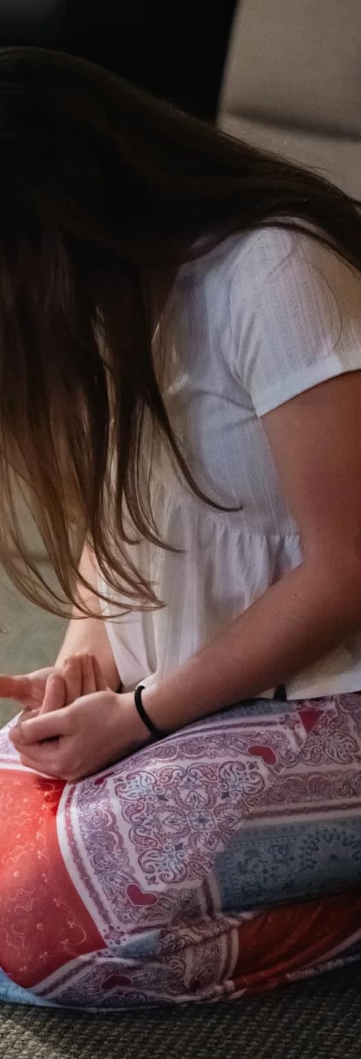 A young woman sitting on the floor with her head bowed in prayer.